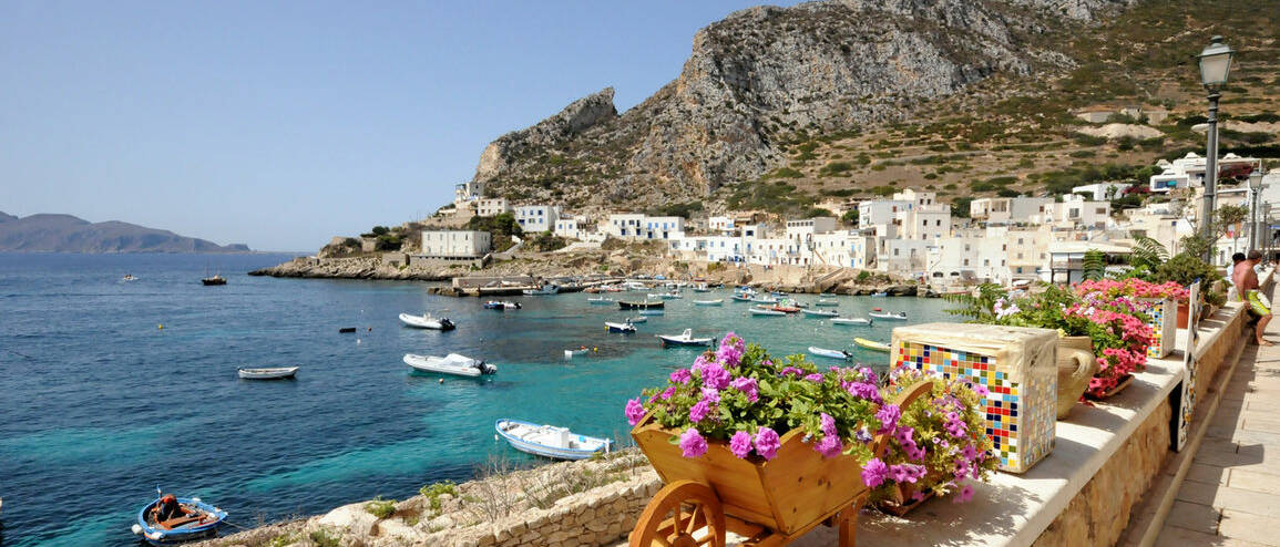 Voyage Italie Iles Egades fleurs et village sur la côte